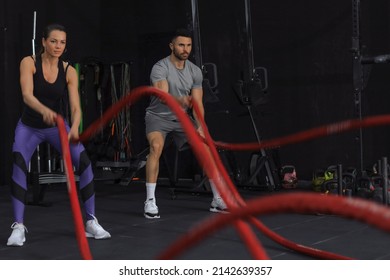 Athletic Young Couple With Battle Rope Doing Exercise In Functional Training Fitness Gym