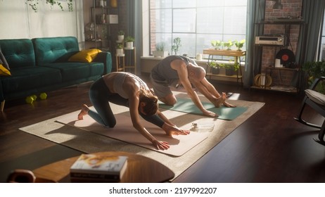 Athletic Young Couple Exercising Together, Stretching And Doing Yoga In The Morning In Sunny Room Of Apartment. Beautiful Man And Woman In Sports Clothes Practising Different Asana Poses On The Mat.