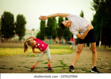 Athletic young father and little daughter do exercises in stadium. Healthy lifestyle - Powered by Shutterstock