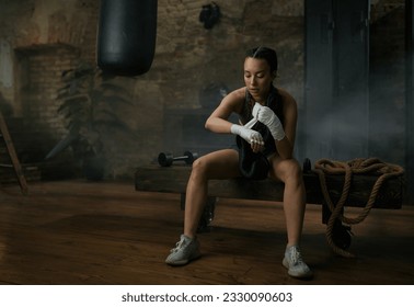 Athletic young female boxer wrapping bandages on her hands - Powered by Shutterstock