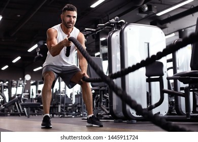 Athletic young man with battle rope doing exercise in functional training fitness gym. - Powered by Shutterstock