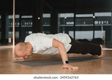 An athletic young man does exercises in the fitness room. A professional guy does yoga in the gym.