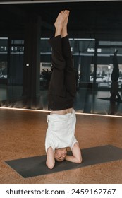 An athletic young man does exercises in the fitness room. A professional guy does yoga in the gym.
