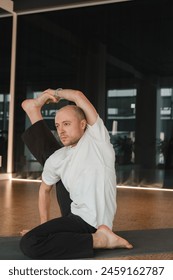 An athletic young man does exercises in the fitness room. A professional guy does yoga in the gym.