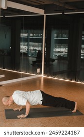 An athletic young man does exercises in the fitness room. A professional guy does yoga in the gym