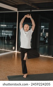 An athletic young man does exercises in the fitness room. A professional guy does yoga in the gym