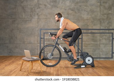 Athletic Young Man Having Stationary Bike Workout At Home