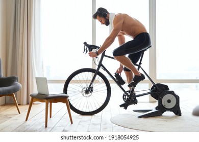 Athletic young man listening to music and riding stationery bike