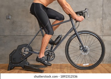 Athletic Young Man Riding Stationery Bike At Home