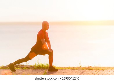 Athletic young man runner stretching legs before run. Fitness, sport and weight loss concept