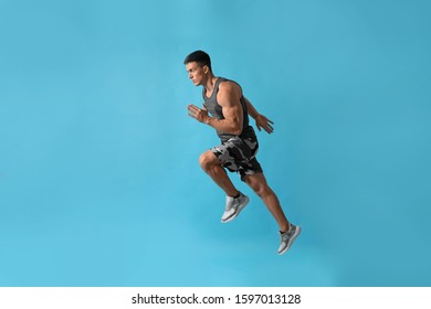 Athletic Young Man Running On Light Blue Background, Side View