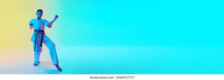 Athletic young martial artist in a kata position, demonstrating focus and concentration against gradient orange blue background in neon light. Concept of sport, martial arts, combat sport, health - Powered by Shutterstock