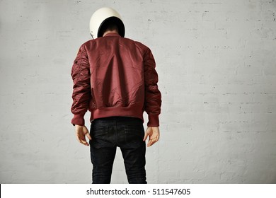 Athletic Young Model In Skinny Jeans, Terracotta Bomber Jacket And White Motorcycle Helmet Isolated On White, Back Shot