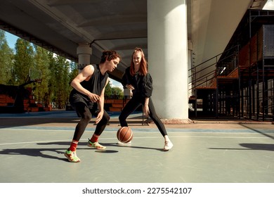 Athletic young people play streetball on the street, a girl and a guy play basketball on the city playground. - Powered by Shutterstock