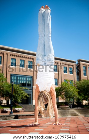 Athletic young woman doing a hand stand In urban setting. 