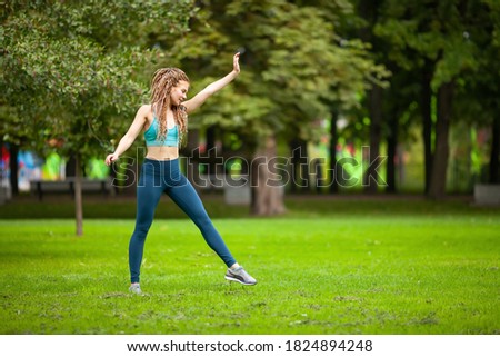 athletic young woman with dreadlocks doing handstand in the park. 
In sportswear.