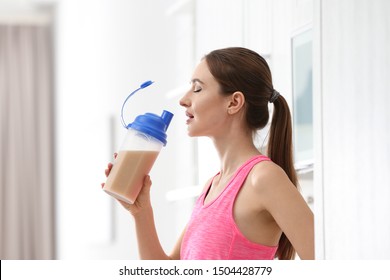 Athletic young woman drinking protein shake in kitchen