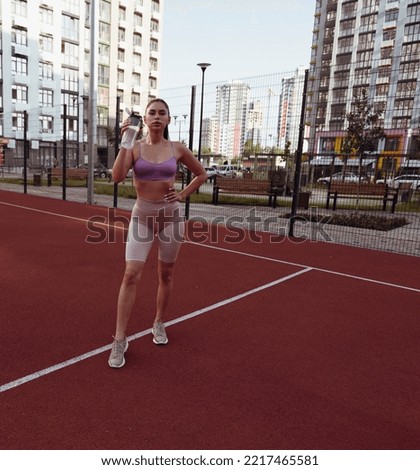 Athletic young woman drinks water at the stadium in the city. Woman workout. Workout city. sports woman