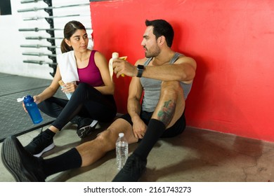 Athletic Young Woman And Man Eating A Snack Together After Finishing Their Daily Workout At The Gym 