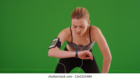 Athletic young woman out jogging checking her smartwatch on green screen - Powered by Shutterstock