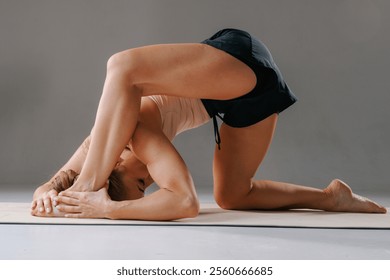 An athletic young woman performs the stretching pose Baddha Parsvakonasana, or Bound Side Angle Pose, during her daily yoga practice at a studio. - Powered by Shutterstock