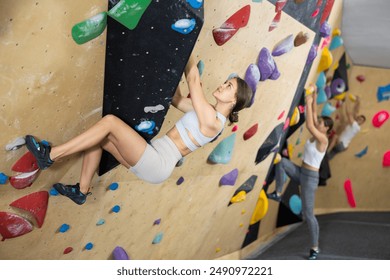 Athletic young woman practicing rock climbing on climbing wall - Powered by Shutterstock