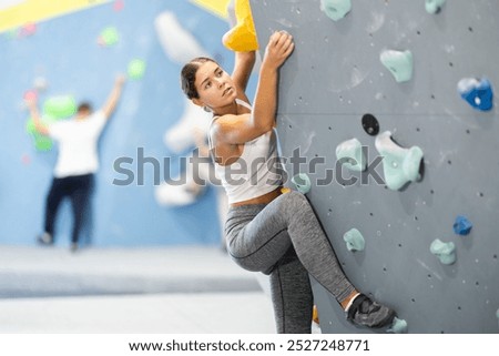 Athletic young woman practicing rock climbing on climbing wall