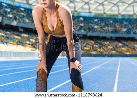 athletic young woman resting after jogging on running track at sports stadium