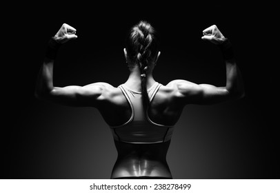 Athletic young woman showing muscles of the back and hands on a isolated black background with clipping path