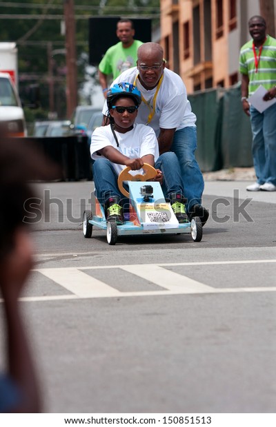  ATLANTA, GA -\
AUGUST 3:  A father pushes his daughter\'s car to begin her run in\
the Cool Dads Rock Soap Box Derby, at the Old 4th Ward Park on\
August 3, 2013 in Atlanta. 