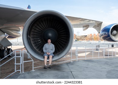 Atlanta, GA - Dec 4, 2022: A middle aged white male sitting inside of a jet engine from a four engine aircraft