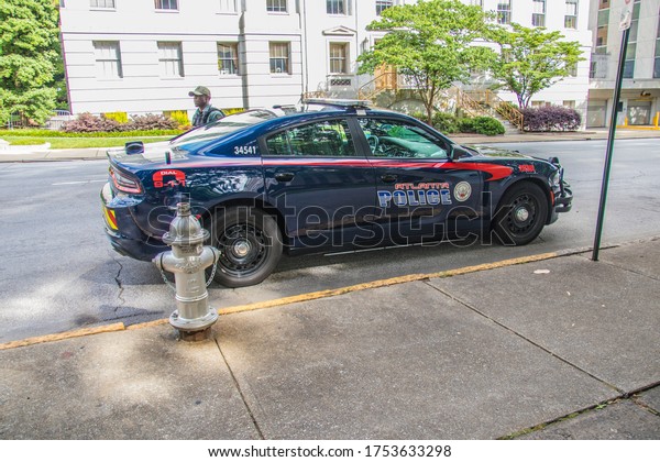 Atlanta, Ga USA - 06 07 20: Downtown\
Atlanta police car side view and officer on\
side