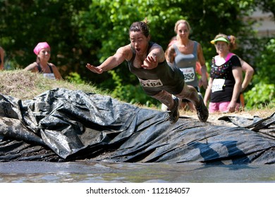 ATLANTA, GA , USA - APRIL 28, 2012:  An Unidentified Woman Competing In The Dirty Girl Mud Run Obstacle Course Race, Dives Into The Mud As She Nears The Finish Line Of The Race On April 28, 2012 In Atlanta.