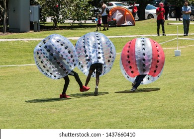 Atlanta, GA / USA - July 28, 2018:  Teenage boys in plastic zorbs bump into each other and knock each other down at the Atlanta Ice Cream Festival in Piedmont Park on July 28, 2018 in Atlanta, GA.
