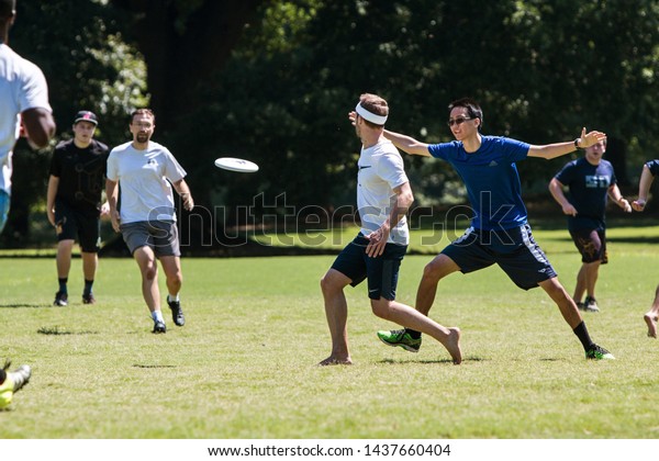 Atlanta, GA / USA - July 28, 2018:  A man\
tosses a frisbee to a teammate in an ultimate frisbee game in\
Piedmont Park on July 28, 2018 in Atlanta,\
GA.