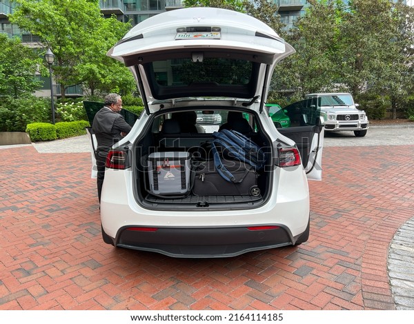 Atlanta, GA USA - May 1, 2022: A Tesla car trunk\
packed with a suitcase and cooler ready for a road trip. Concept\
traveling by car.
