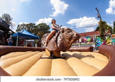 Atlanta, GA, USA - September 23, 2017:  A young woman tries to stay upright as she rides a mechanical bull at the East Atlanta Strut, a fall festival on September 23, 2017 in Atlanta, GA. 