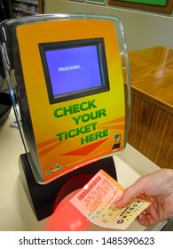 ATLANTA, GEORGIA - AUGUST 22, 2019 : Woman Using Lotto Machine Kiosk To Check Powerball Lottery Ticket For Winning Numbers.