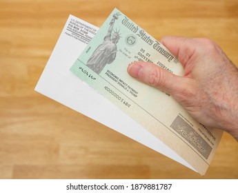 ATLANTA, GEORGIA - December 21, 2020 : United States Treasury Economic Impact Check Including President Donald J. Trump Printed Name. Man Holding Stimulus Check For Coronavirus COVID-19 Pandemic Relie