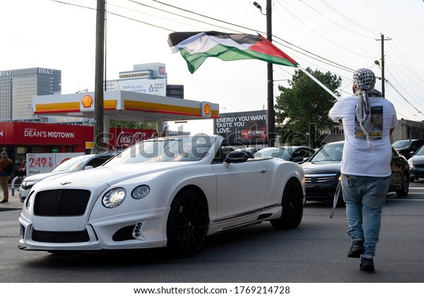ATLANTA, GEORGIA, USA - 03 July, 2020: A\
protester dances and waves a flag at cars to spread awareness of\
injustices against Palestinian\
people.