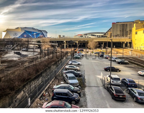 ATLANTA,\
GEORGIA / USA - January 30, 2019: Cars parked at the Gulch and Rail\
Yard overlooking CNN World Headquarters, State Farm Arena, and\
Mercedes-Benz Stadium hosting NFL Super Bowl\
53.