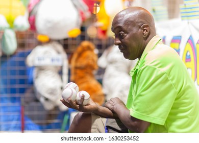 Atlanta, Georgia, USA - March 30, 2017: Carnival Worker Waiting On A Customer With Baseballs In His Hand.