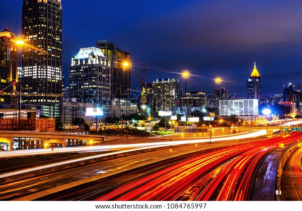 Atlanta, USA. Illuminated Midtown in Atlanta, USA\
at night. Car traffic, illuminated buildings and dark sky. Car\
traffic trails