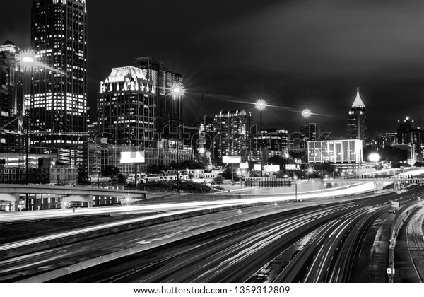 Atlanta, USA. Illuminated Midtown in Atlanta, USA\
at night. Car traffic, illuminated buildings and dark sky. Car\
traffic trails. Black and\
white