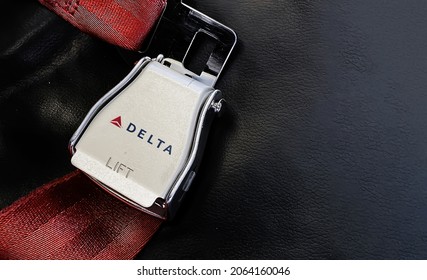 Atlanta, USA, October 2021: Red lap belt of an empty seat inside an airplane with the Delta Airlines logo printed on the metal. Delta is one of the major airlines of the United States