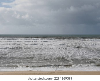 Atlantic costal landscape. Calming horizontal symmetry. Sandwich composition, two wide stripes: grey gloomy sky and foamed water intertwined with two ribbons of: dark sea water and golden sand. - Powered by Shutterstock