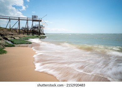 Atlantic ocean waves on the coast of France with sandy beach and traditional fishing huts on rocky coastline near La Rochelle - Powered by Shutterstock