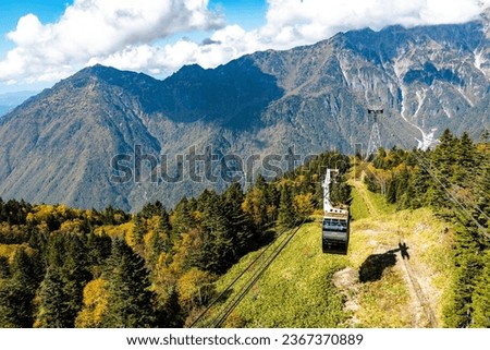 The atmosphere of the main tourist attraction Shin Hotaka in the autumn colors with a cable car and ropeway serving tourists. Japan Alps, Shinhotaka Ropeway and Fall foliage.