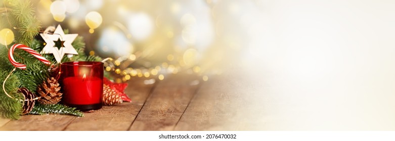 Atmospheric Advent and Christmas decoration with a red candle, wooden star and evergreen fir branches on dark rustic wooden planks, wide panoramic format, copy space,banner.