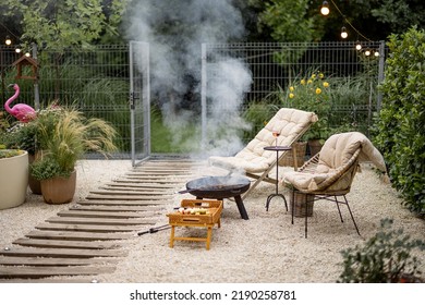 Atmospheric Backyard With Fire And Lounge Chairs At Dusk On Nature. Grilling Food On Fire Bowl